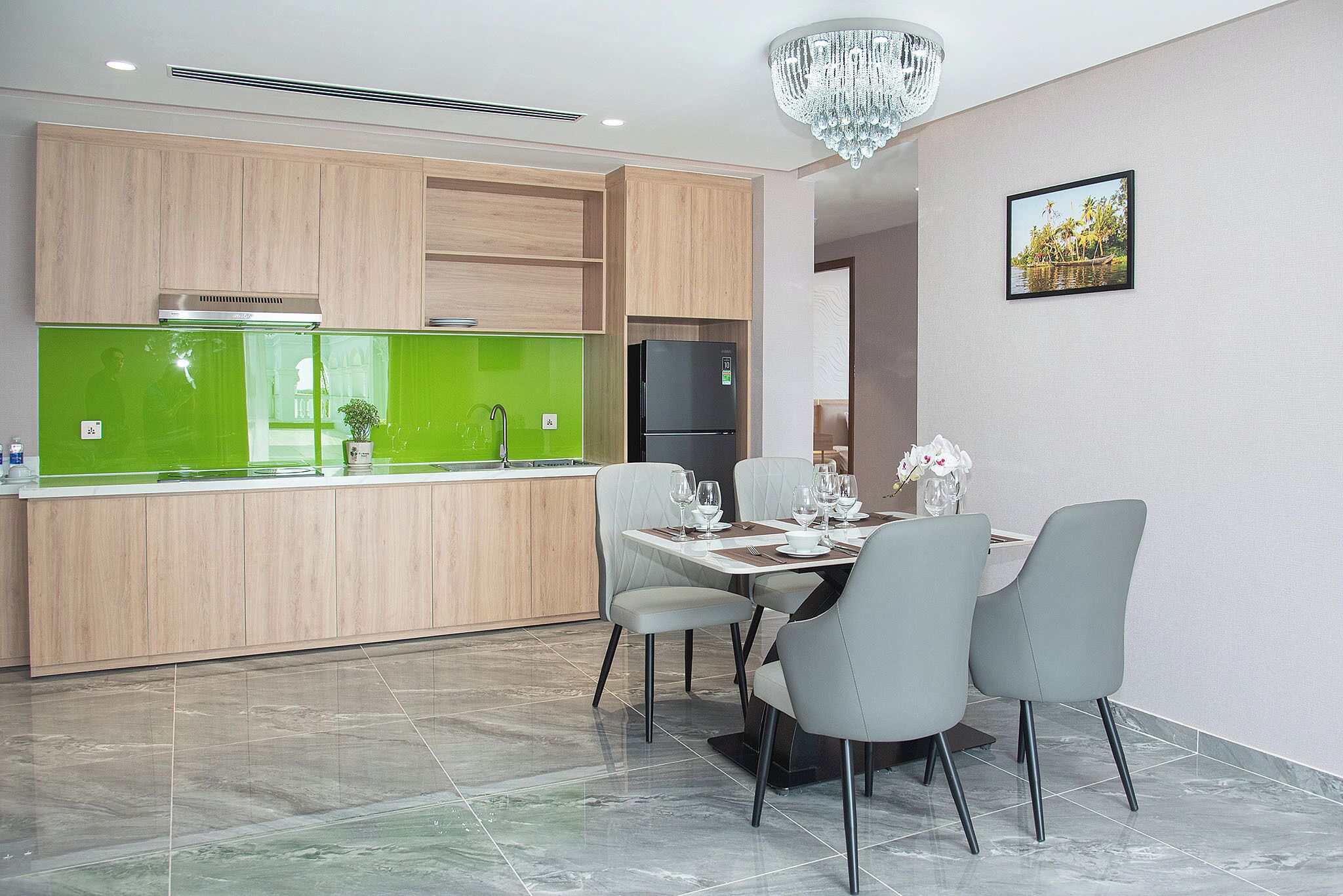 A modern kitchen with wooden cabinets, a green backsplash, and a dining area with a table set for four.