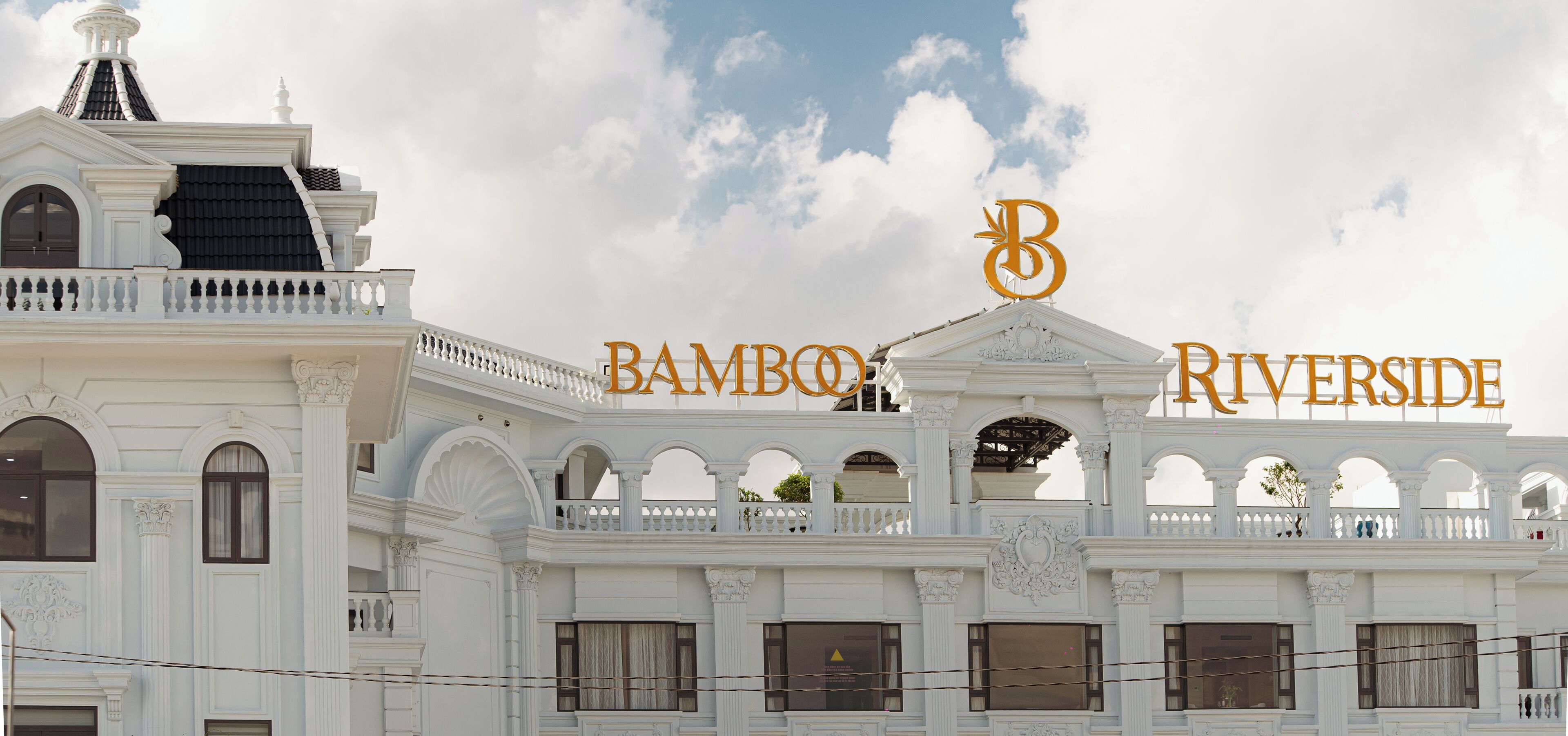 Un imposant bâtiment sur lequel on peut voir une grande enseigne indiquant « Bamboo Riverside », caractérisé par une architecture classique avec des colonnes et des arches.