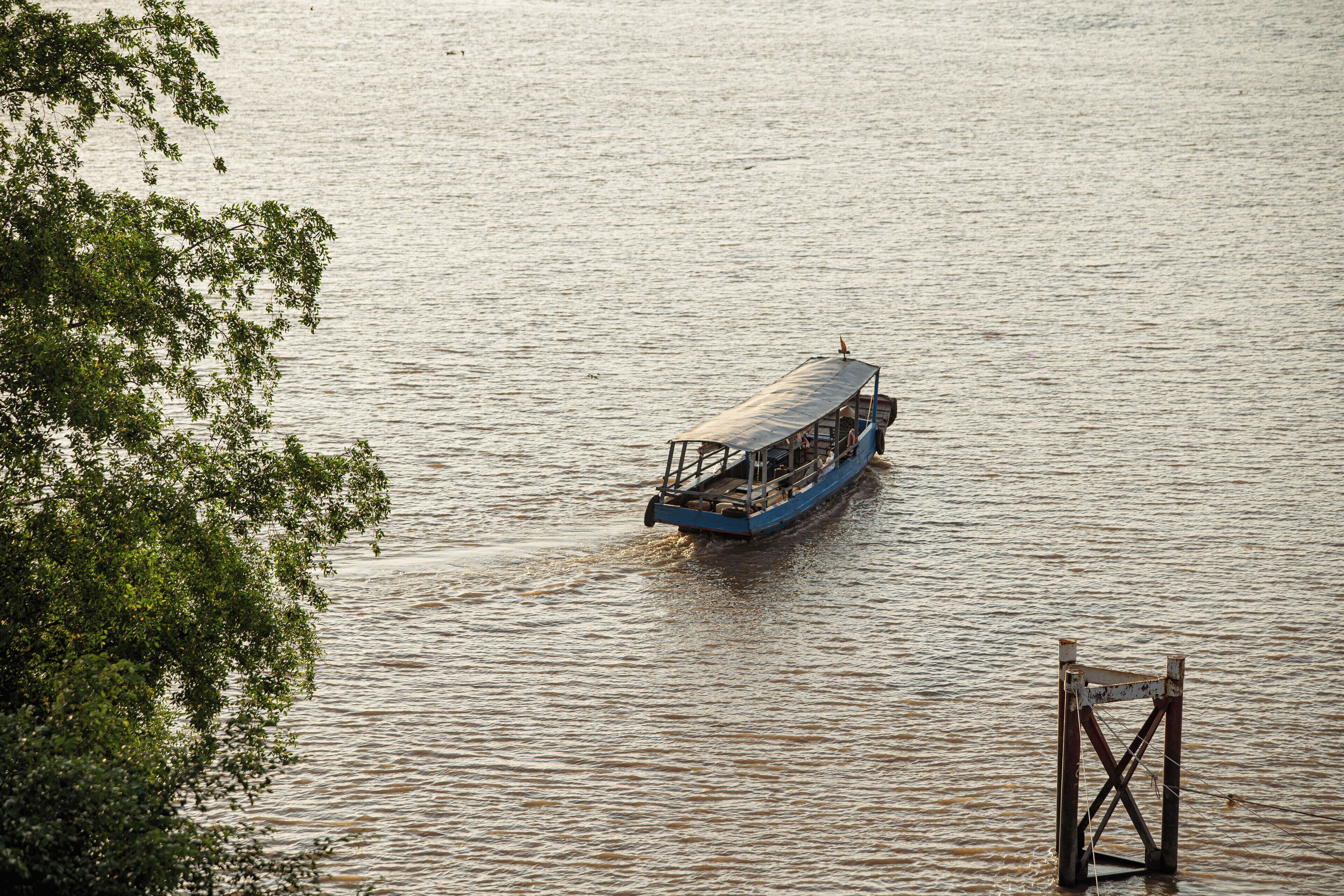 Un bateau sur une rivière, avec une structure en bois au premier plan.