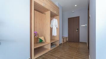 A hallway with a wooden wardrobe, a white robe hanging, and a shoe rack.