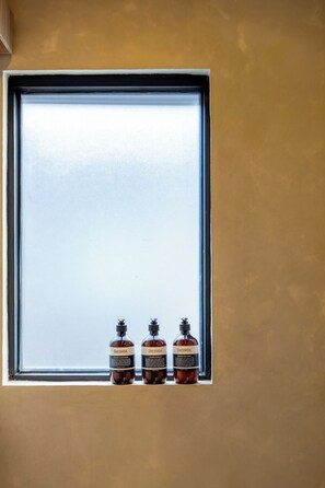 A window with three bottles of liquid in a window sill. - Inhale Loft Villa by Betterplace (Canggu)