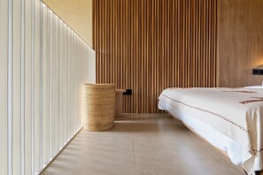 A modern hotel room with a large bed, a wooden slat wall, a woven waste basket, and a light-colored floor. - Inhale Loft Villa by Betterplace (Canggu)