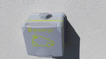 Een grijs, rechthoekig object met de tekst 'Greenup System' en een icoon van een auto, bevestigd aan een witte muur.