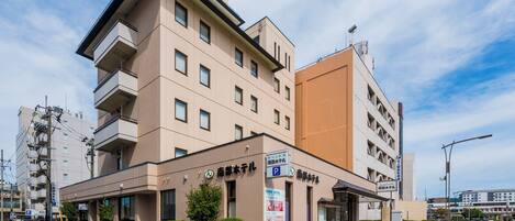 A modern hotel with multiple floors, a prominent entrance, and a parking sign.