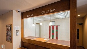 A reception desk with a wooden counter, a bench, and a sign that reads "Cashier." - nanbuhotel (Kitakami)
