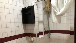 A bathroom with white and red tiles, a toilet, a shower with a handheld showerhead, and a towel rack.