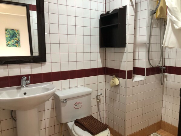 A bathroom with a white sink, a toilet, and a shower. There is a framed picture on the wall and a towel rack. - Sutus Court 7 (Pattaya)