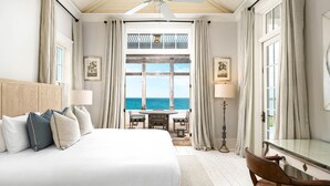 Una habitación de hotel con una cama grande, un escritorio y vista al océano.