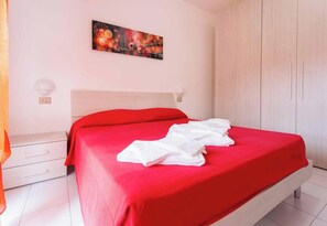 Une chambre d’hôtel avec un lit, une table de chevet, une armoire et un tableau au mur.