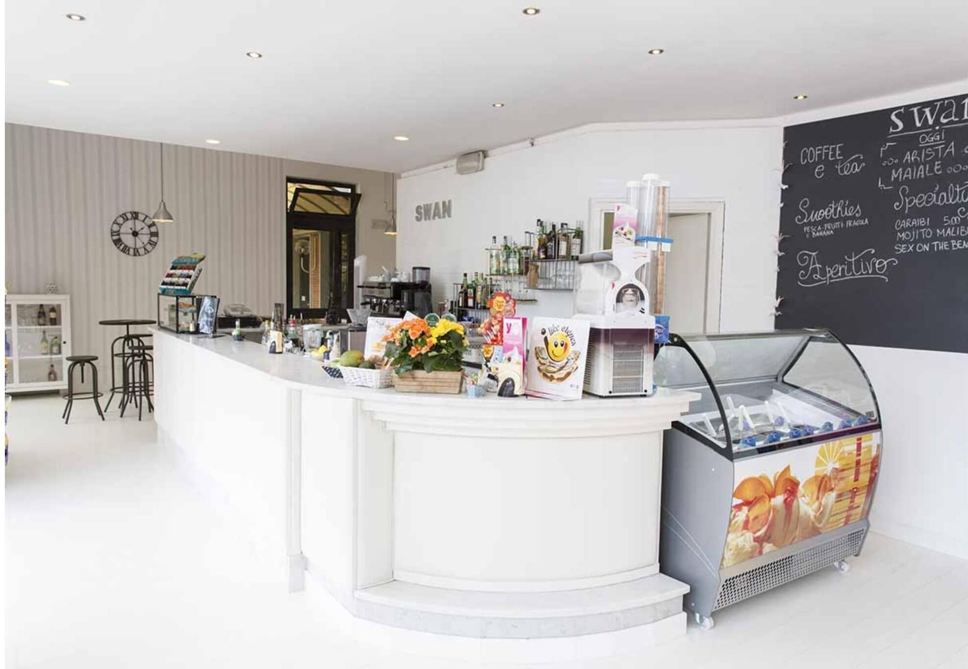 Un caffè moderno con un bancone bianco, una macchina da caffè e una lavagna con il menu.