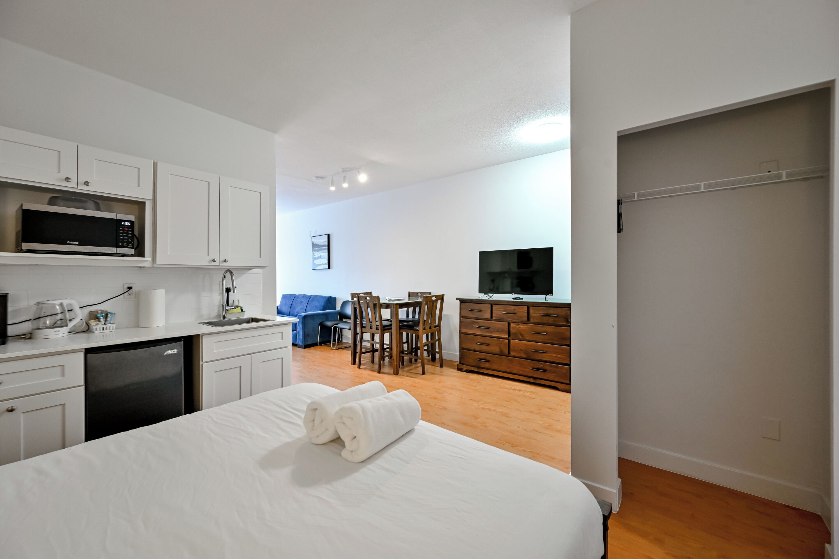 Habitación de hotel con cama, microondas, lavamanos, zona de comedor y televisión.