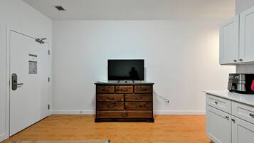 A room with a wooden dresser, a television on top, and a microwave on the right.