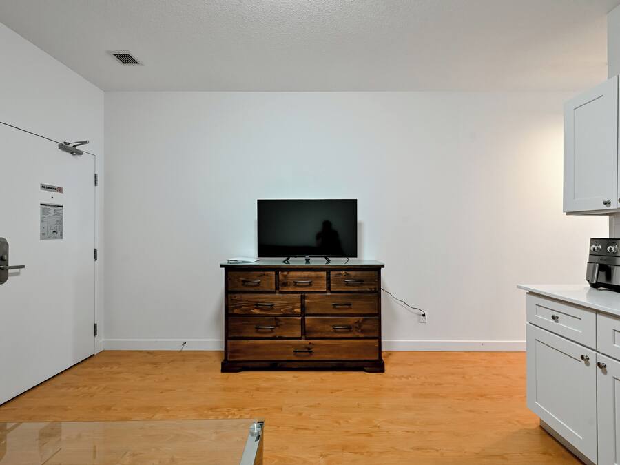 A room with a wooden dresser, a television on top, and a microwave on the right.