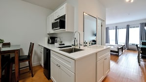 Una cocina moderna con muebles blancos, un lavabo doble y una zona de comedor con mesa y sillas de madera.