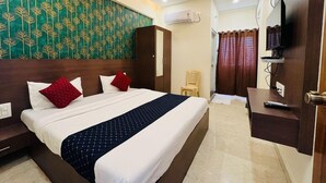 Une chambre d’hôtel avec un lit, un bureau, une télévision et une armoire.