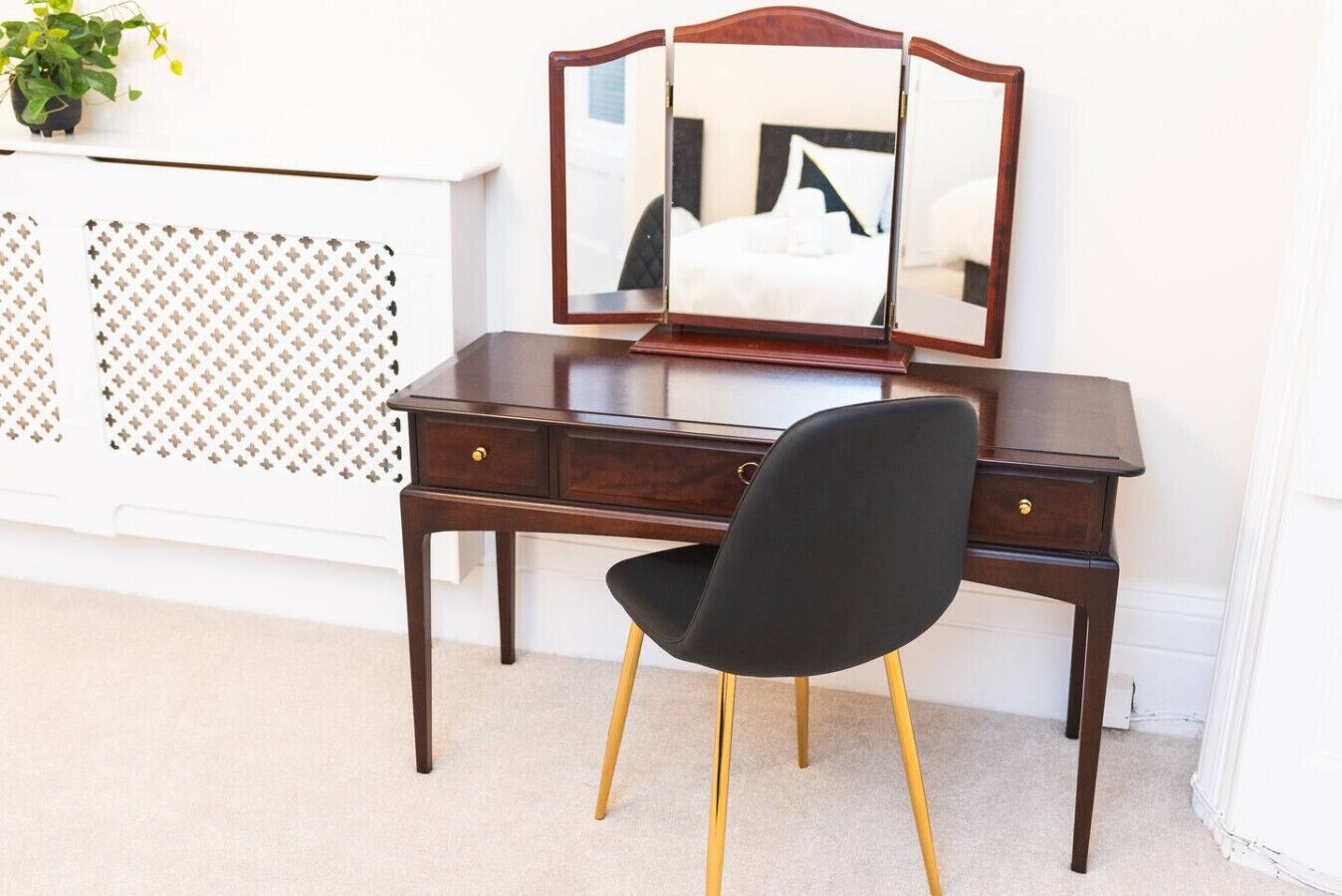 A dark wooden desk with a black chair and a mirror.