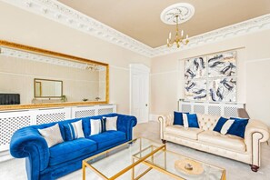 A living room with two sofas, a glass coffee table, a chandelier, and a large mirror with a gold frame. - Sneyd Park escape | Garden views by MyCityHaven (Sneyd Park)