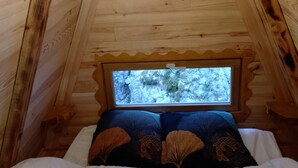 Une pièce chaleureuse, aménagée dans un chalet en bois, avec un lit, une fenêtre et un luminaire.