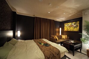 A hotel room with a large bed, a sofa, a coffee table, and a painting on the wall. - Le Ciel Spa & Resort (Tsurugashima)