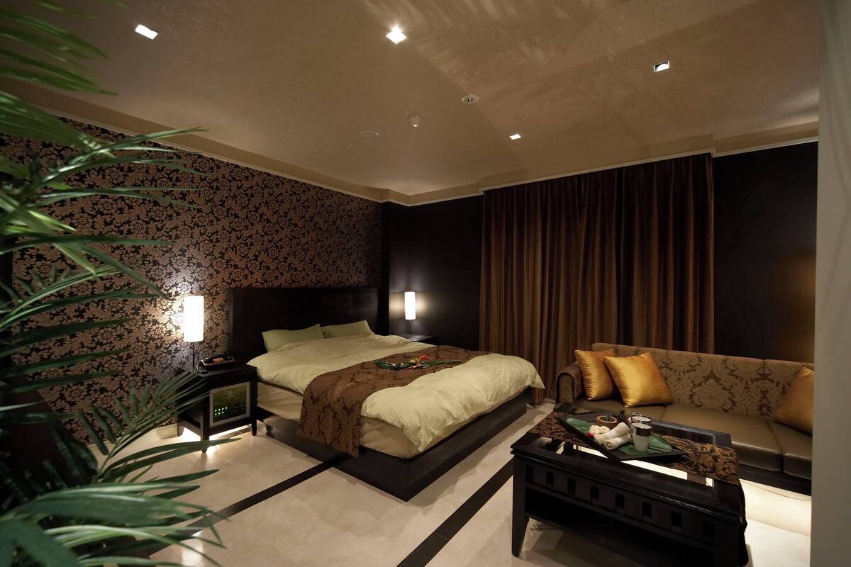 A hotel room with a bed, a sofa, a nightstand, and a coffee table.
