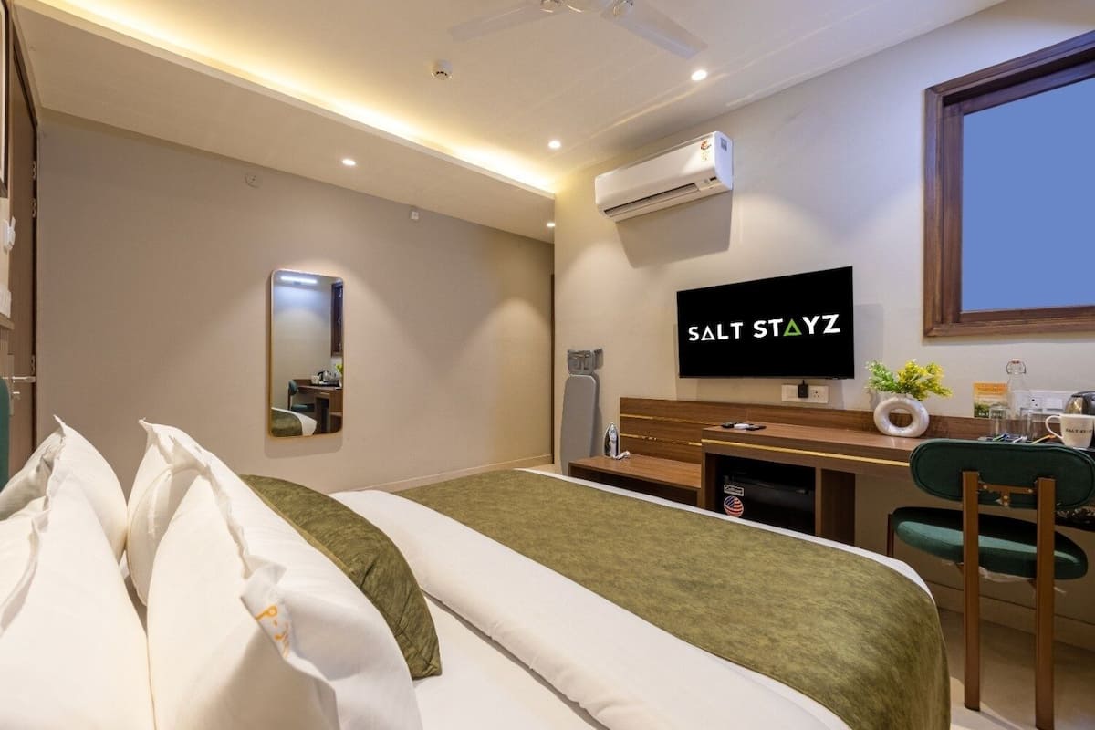 Une chambre d’hôtel équipée d’un lit, d’un bureau, d’une télévision et d’un climatiseur fixé au mur.