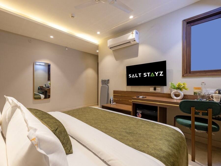 Ein Hotelzimmer mit einem Bett, einem Schreibtisch, einem Fernseher und einer Klimaanlage.