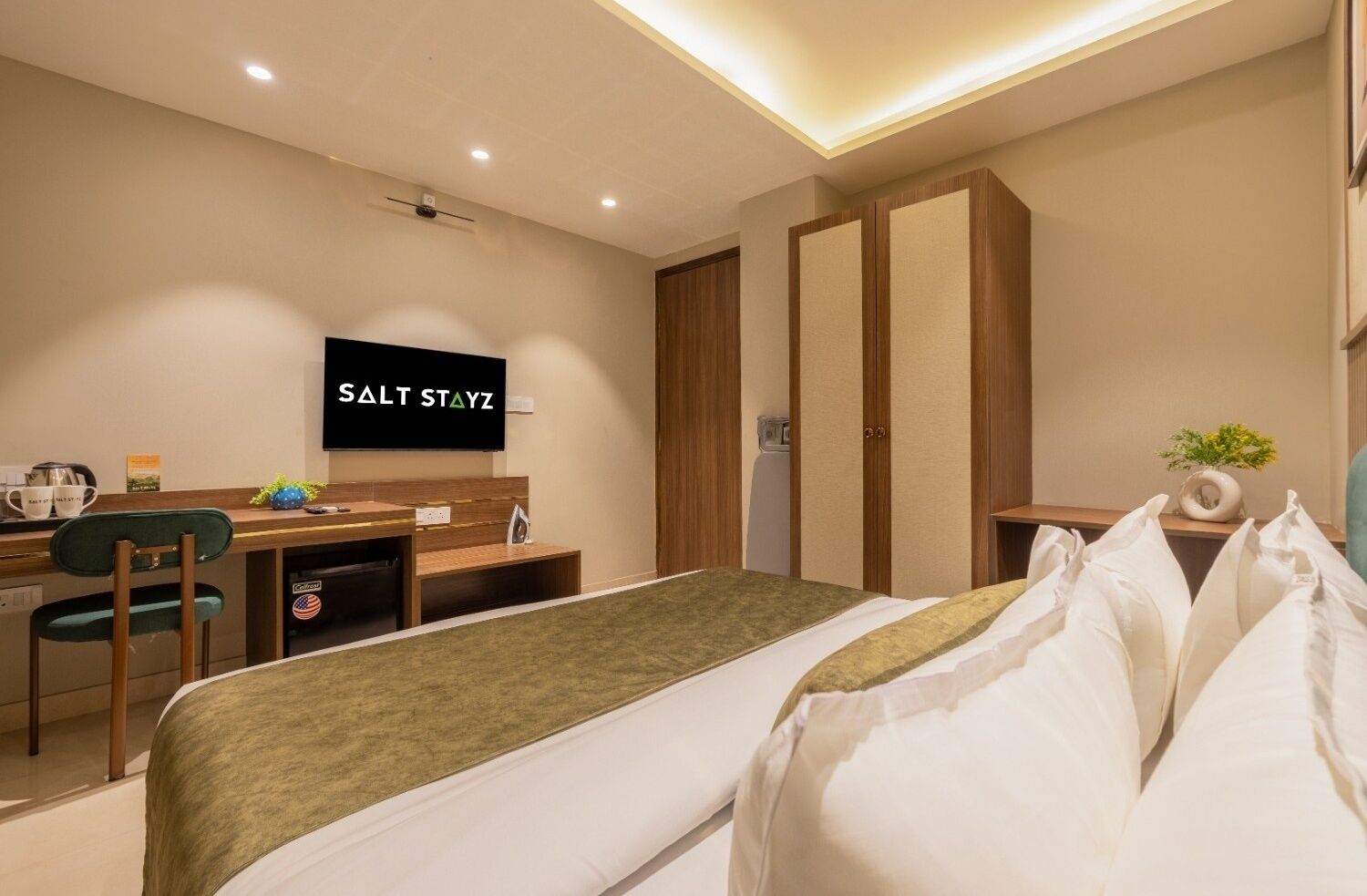 Quarto de hotel moderno com cama, escrivaninha, cadeira, televisão e guarda-roupa.