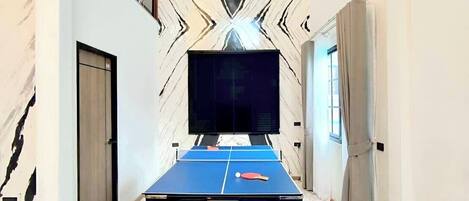 A spacious room with a pool table, a television, and a marble-patterned wall.