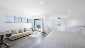 A modern bedroom with a large bed, a sofa, and a dining table. - 2 Oceanfront Homes w/ Rooftop Deck, Views & Steps to the Sand (Oceano)