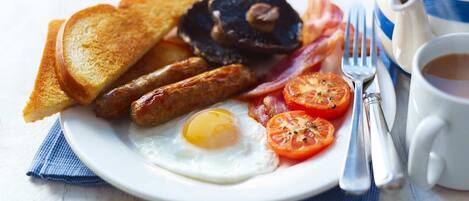 A plate of breakfast food including toast, sausages, bacon, eggs, and tomatoes.