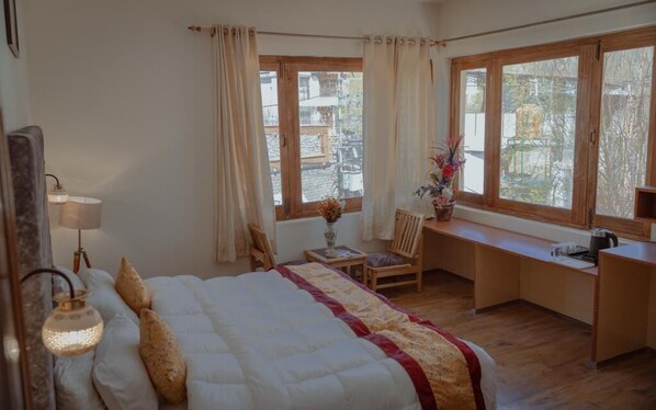 Une chambre à coucher avec un lit, un bureau, une chaise et une fenêtre avec des rideaux.