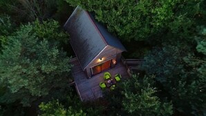 An aerial view of a cabin surrounded by dense forest.