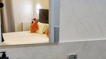 A bathroom with a sink, mirror, toiletries, and a towel rack.