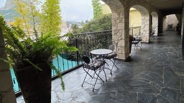 A stone-floored patio with a pool, outdoor seating, and a view of a mountain.