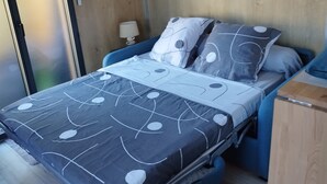 Une chambre à coucher de taille réduite, comprenant un lit, une table de chevet, une lampe et un mur en bois.