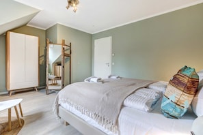 A bedroom with a bed, a wardrobe, a mirror, and a door.