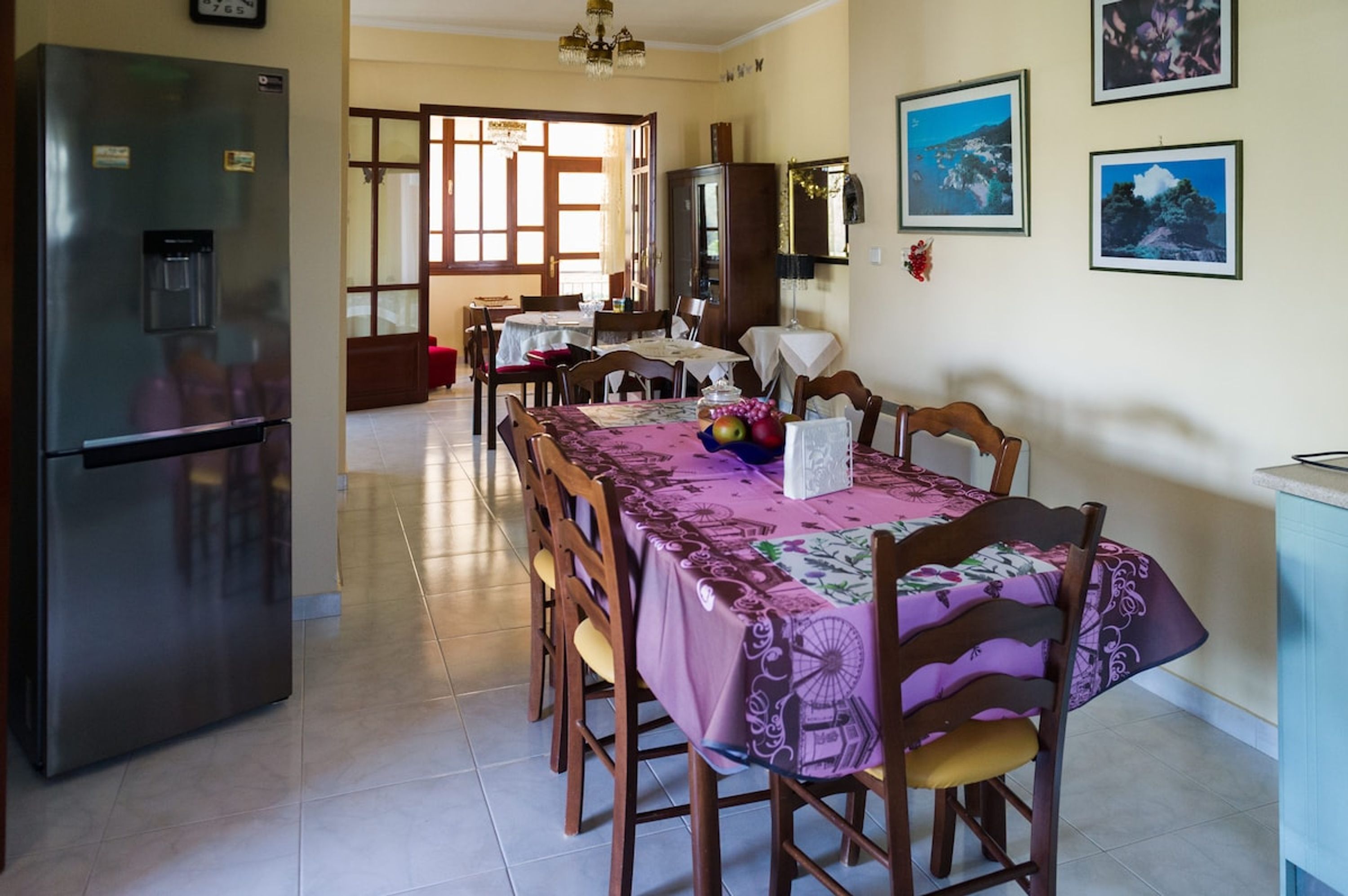 A dining area with a table set for four, a refrigerator, and a cabinet.