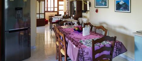 A dining area with a table set for four, a refrigerator, and a cabinet.