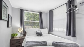 A neatly arranged bedroom with a bed, bedside table, lamp, and curtains.