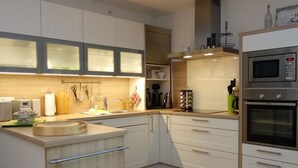 Una cocina moderna con armarios blancos, encimera de madera, horno integrado y microondas.