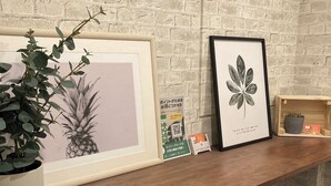 Ein Holzboden mit gerahmten Kunstwerken, einer Topfpflanze und einem kleinen Hocker.
