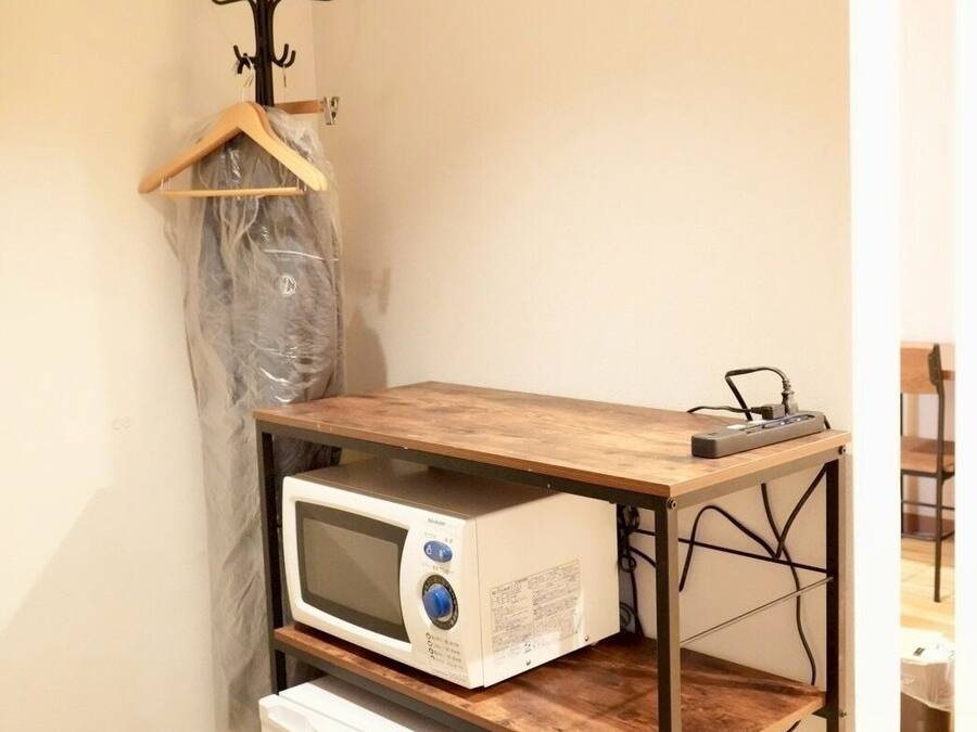 A kitchenette with a microwave, refrigerator, and wooden table.