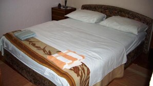 A neatly made bed with a floral-patterned bedspread and a folded towel on the side. - Apartments Miloš (Malinska-Dubasnica)