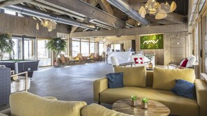 A spacious lobby with a pool table, comfortable seating, and a large screen displaying a logo.
