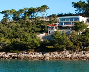 A coastal property with a large building, a stone wall, and a rocky shoreline. - Villa Lukrecia -Stunning Sea View Retreat (Korcula)