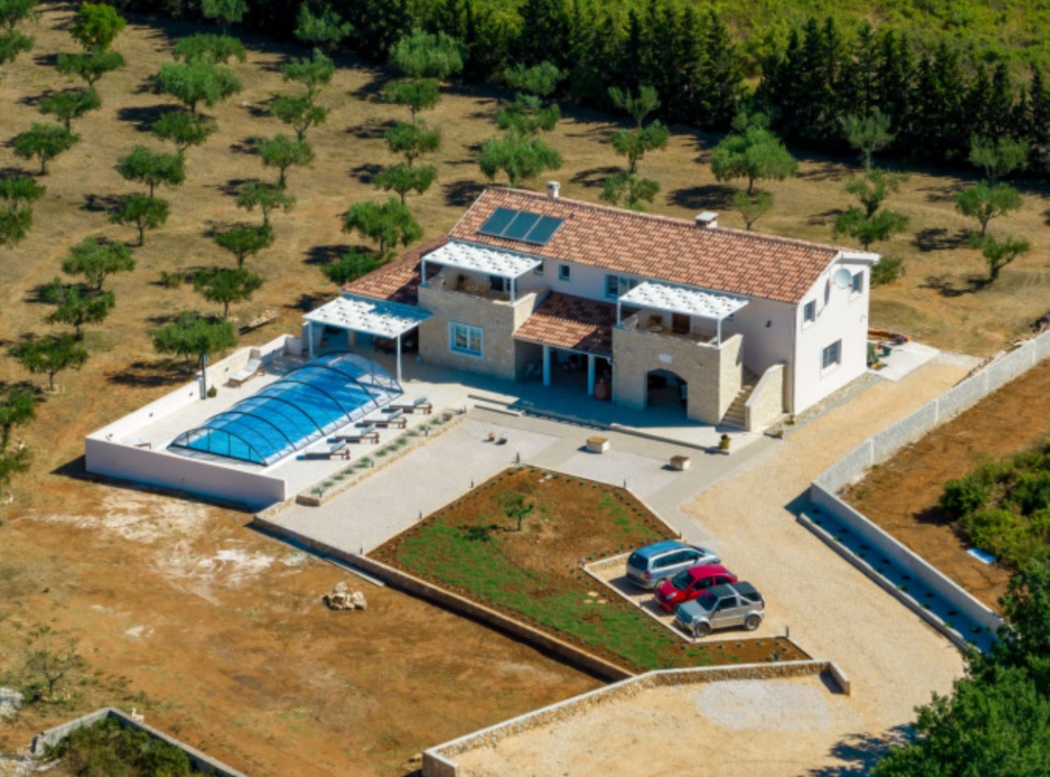 Vista aérea de una villa moderna con piscina, varias habitaciones para huéspedes y un patio cubierto.