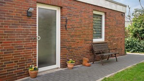 A brick building with a glass door, a bench, and potted plants. - Apartment 'Haus Meyer' with Private Terrace, Private Garden and Wi-Fi (Cuxhaven)
