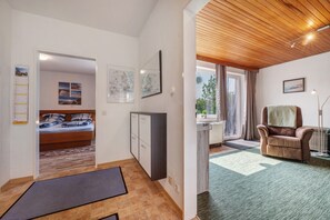 Quarto com cama, escrivaninha, cadeira e vista para o exterior.