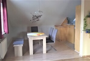 A small, compact kitchen with a dining table and chairs, a radiator, and a wall-mounted light fixture. - Apartment 'Beim Ried' with Balcony and Wi-Fi (Bad Waldsee)