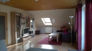 Amplia sala de estar con televisor, sofá, mesa de centro y tragaluz.